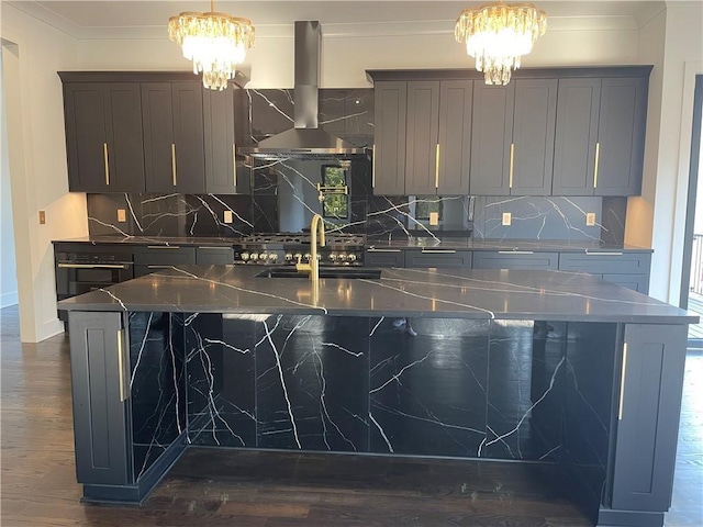 kitchen featuring an inviting chandelier, crown molding, exhaust hood, and a center island with sink