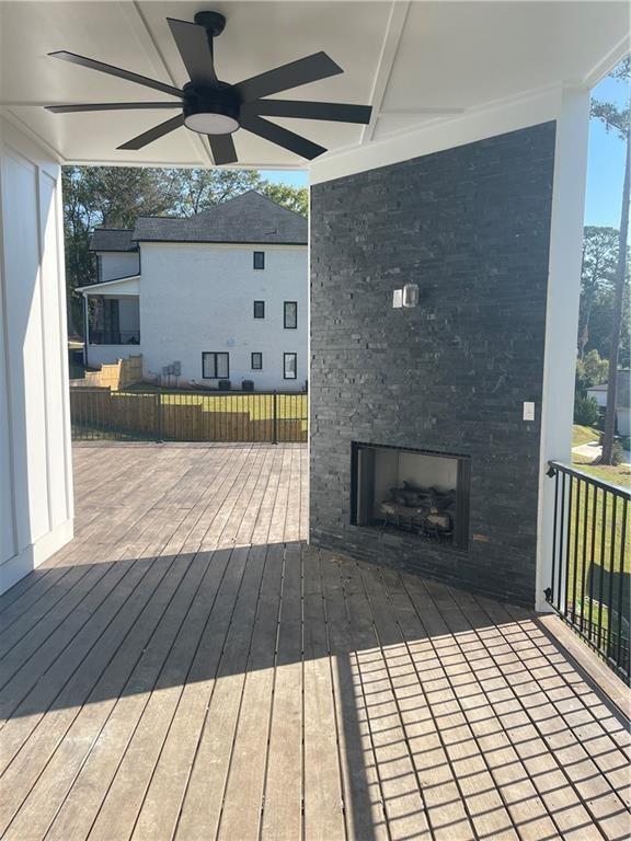 wooden deck with ceiling fan and an outdoor fireplace