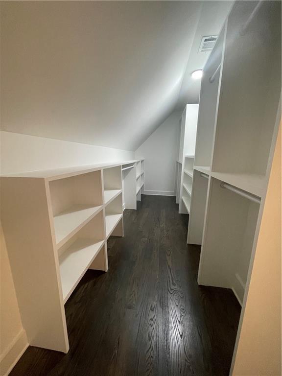 walk in closet with lofted ceiling and dark hardwood / wood-style flooring