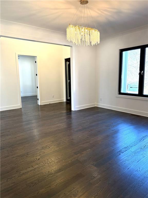 empty room with ornamental molding, dark hardwood / wood-style floors, and a chandelier