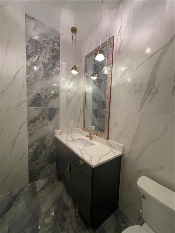 bathroom featuring vanity, tile walls, and toilet