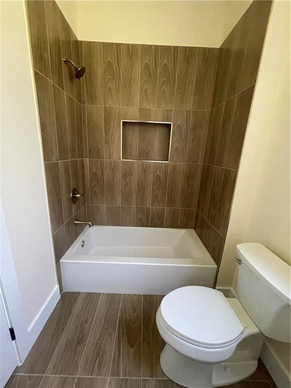 bathroom featuring tiled shower / bath, hardwood / wood-style floors, and toilet