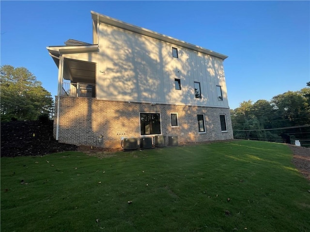 rear view of property with central AC unit and a yard