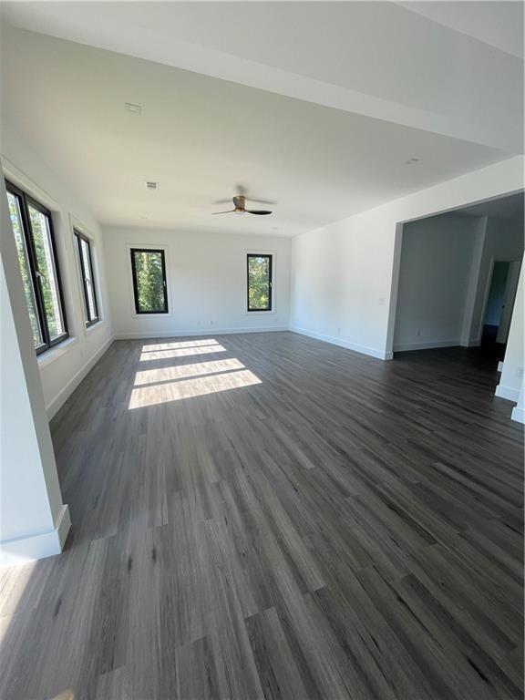 unfurnished living room featuring ceiling fan and dark hardwood / wood-style floors