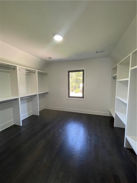 unfurnished bedroom with lofted ceiling and dark wood-type flooring