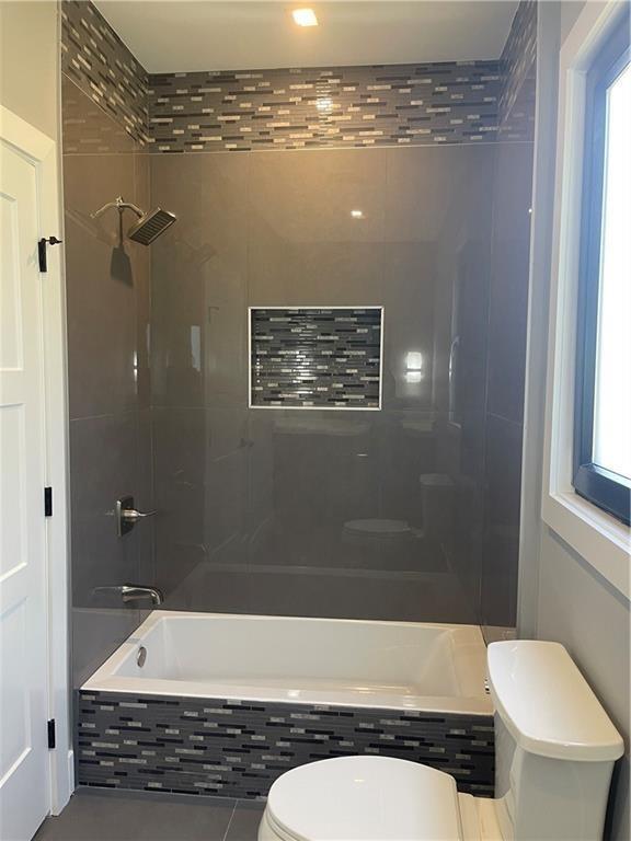 bathroom featuring tiled shower / bath combo and toilet