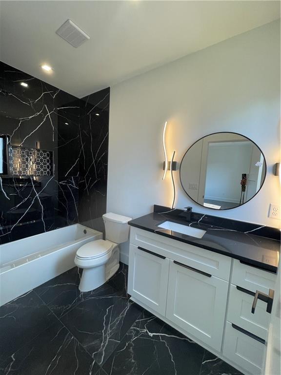 full bathroom with vanity, tiled shower / bath, and toilet