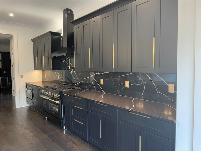 kitchen featuring wall chimney range hood, dark hardwood / wood-style floors, tasteful backsplash, ornamental molding, and range with two ovens