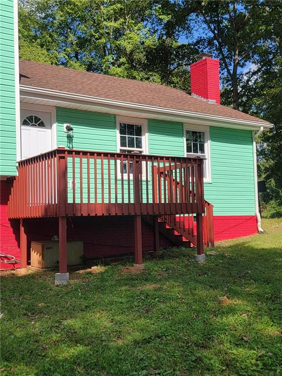 rear view of property with a deck and a lawn