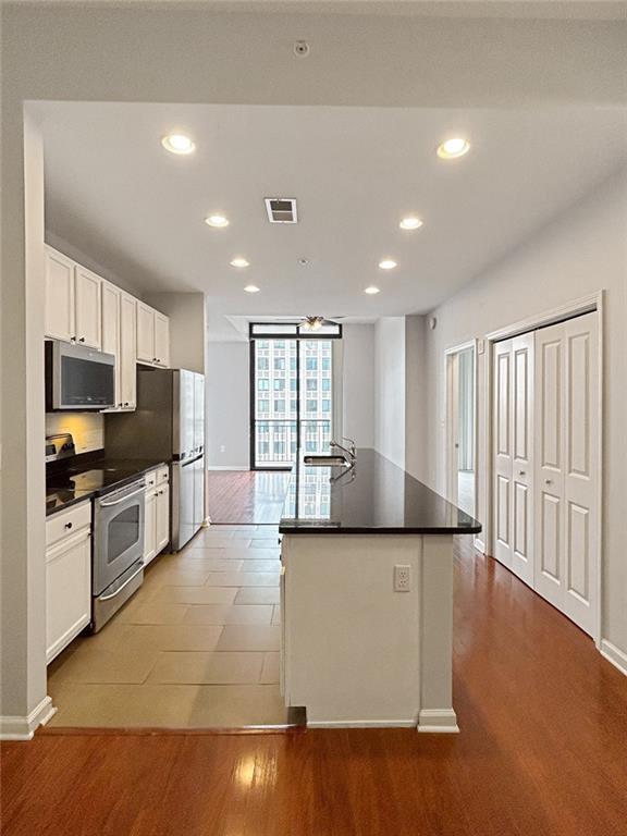 3040 Peachtree Rd NW Unit 1501, Atlanta, GA 30305 - kitchen featuring appliances with stainless steel finishes, recessed lighting, dark countertops, white cabinets, and an island with sink