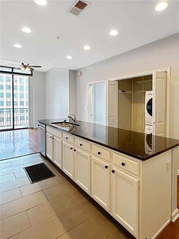3040 Peachtree Rd NW Unit 1501, Atlanta, GA 30305 - kitchen with stacked washer and clothes dryer, dishwasher, dark tile patterned floors, a sink, and ceiling fan