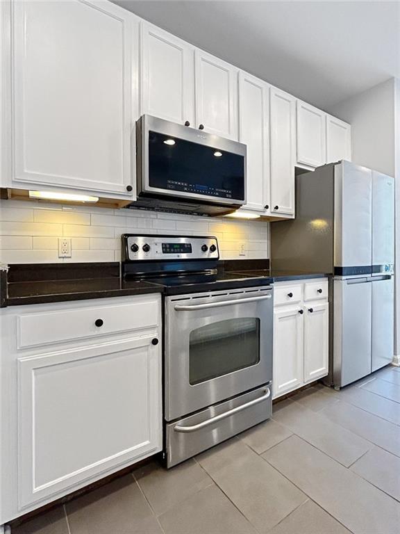 3040 Peachtree Rd NW Unit 1501, Atlanta, GA 30305 - kitchen featuring stainless steel appliances, dark countertops, white cabinets, and backsplash