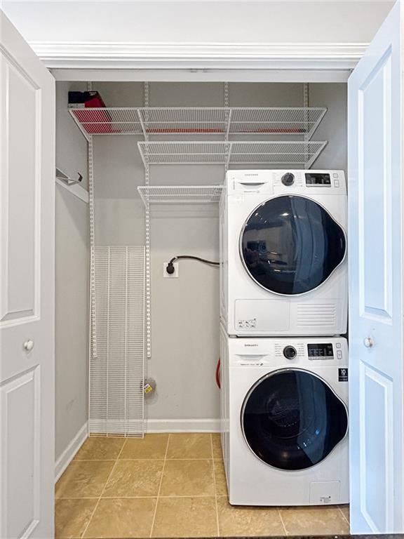 3040 Peachtree Rd NW Unit 1501, Atlanta, GA 30305 - laundry area featuring stacked washer and clothes dryer, baseboards, and light tile patterned floors