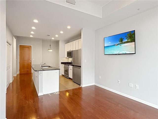 3040 Peachtree Rd NW Unit 1501, Atlanta, GA 30305 - kitchen featuring appliances with stainless steel finishes, dark countertops, wood finished floors, white cabinetry, and a sink