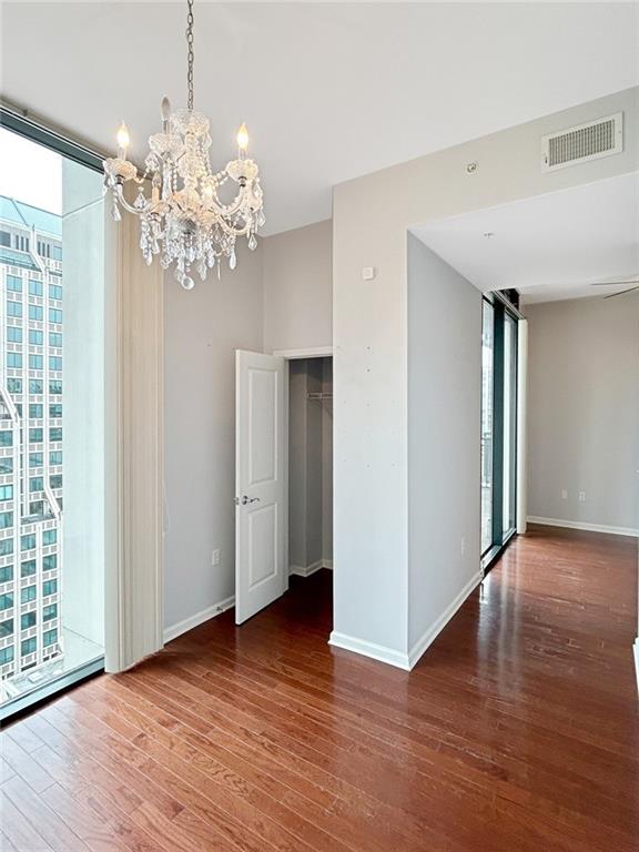 3040 Peachtree Rd NW Unit 1501, Atlanta, GA 30305 - spare room with wood finished floors, a chandelier, baseboards, and a wall of windows