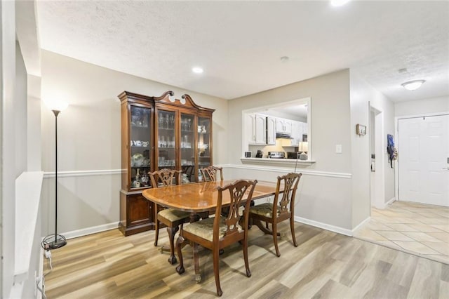 dining room featuring recessed lighting, baseboards, light wood finished floors, and a textured ceiling