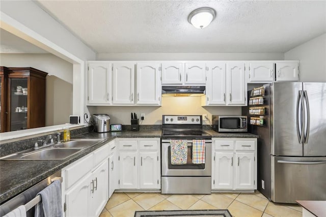 kitchen with appliances with stainless steel finishes, dark countertops, a sink, white cabinets, and under cabinet range hood
