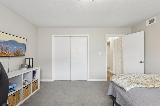 carpeted bedroom with visible vents, baseboards, and a closet