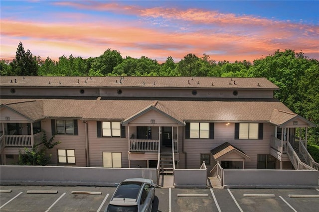 property at dusk with uncovered parking and stairway