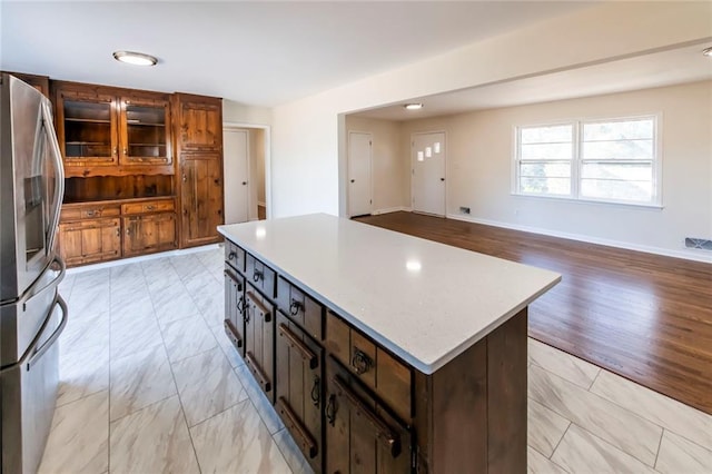 kitchen with dark brown cabinetry, stainless steel fridge with ice dispenser, and a kitchen island