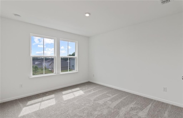 empty room featuring carpet floors, visible vents, and baseboards