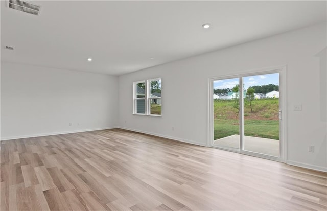 spare room with a healthy amount of sunlight, light wood-style floors, and visible vents