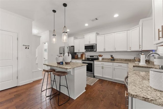 kitchen featuring appliances with stainless steel finishes, a center island, white cabinets, and dark hardwood / wood-style floors