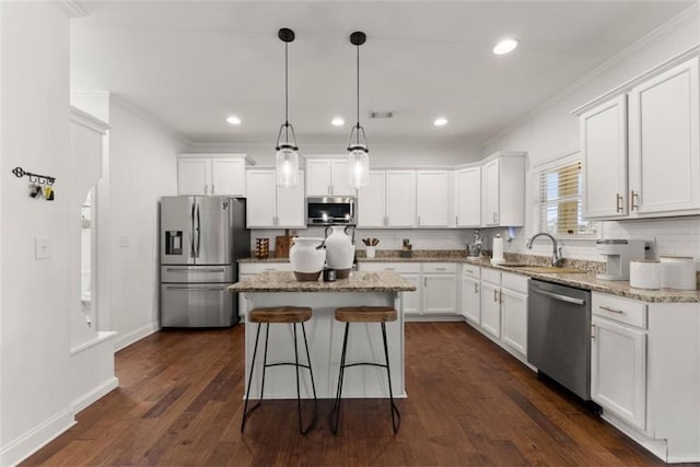 kitchen featuring sink, white cabinetry, hanging light fixtures, appliances with stainless steel finishes, and a kitchen island