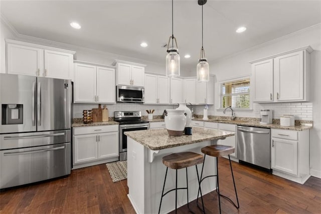 kitchen with stainless steel appliances, a kitchen island, white cabinets, and decorative light fixtures