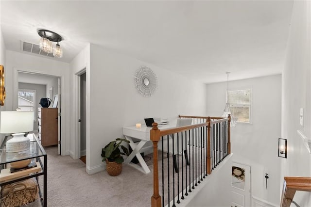 corridor featuring an inviting chandelier and light colored carpet