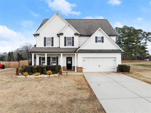 view of front of property featuring a porch, a garage, and a front lawn