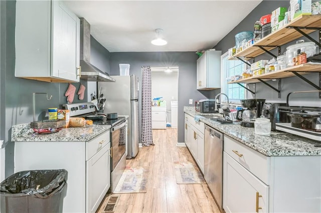 504 J C Daniel Rd, Carrollton, GA 30117 - kitchen featuring stainless steel appliances, wall chimney exhaust hood, open shelves, light wood finished floors, and washer / clothes dryer