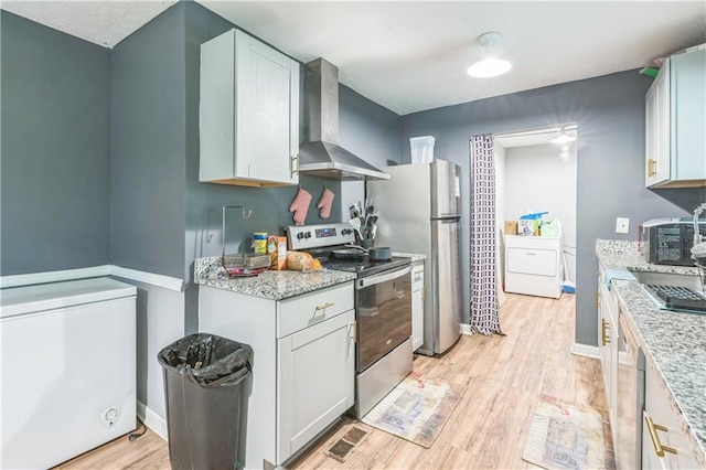 504 J C Daniel Rd, Carrollton, GA 30117 - kitchen featuring wall chimney exhaust hood, appliances with stainless steel finishes, washer / clothes dryer, and light wood-type flooring
