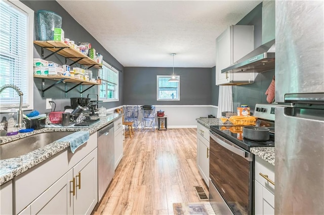 504 J C Daniel Rd, Carrollton, GA 30117 - kitchen featuring appliances with stainless steel finishes, wall chimney range hood, a sink, light wood-style floors, and light stone counters