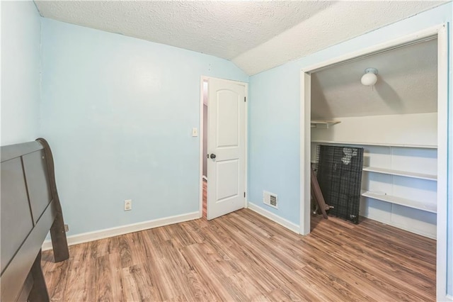 504 J C Daniel Rd, Carrollton, GA 30117 - unfurnished bedroom featuring light wood-style floors, a textured ceiling, baseboards, lofted ceiling, and a closet