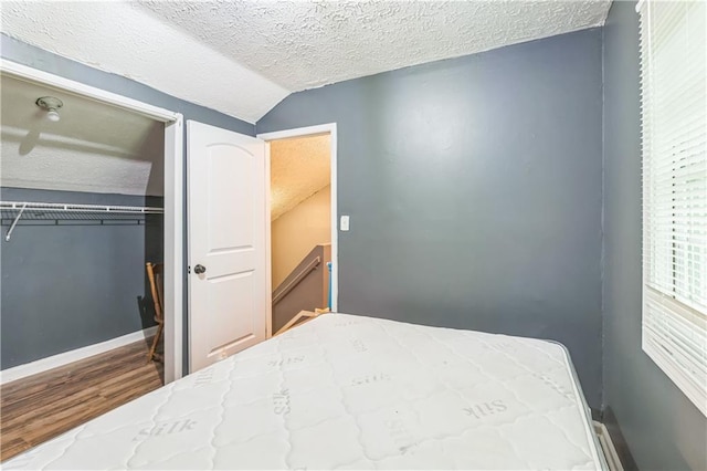 504 J C Daniel Rd, Carrollton, GA 30117 - bedroom with a textured ceiling, wood finished floors, vaulted ceiling, a closet, and baseboards