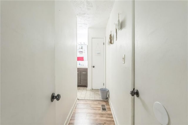 504 J C Daniel Rd, Carrollton, GA 30117 - hall with light wood finished floors, a textured ceiling, baseboards, and a sink