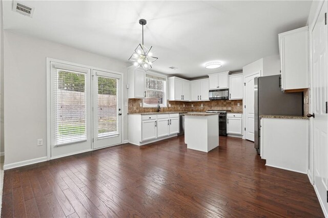 kitchen featuring sink, light stone counters, a center island, stainless steel dishwasher, and white cabinets