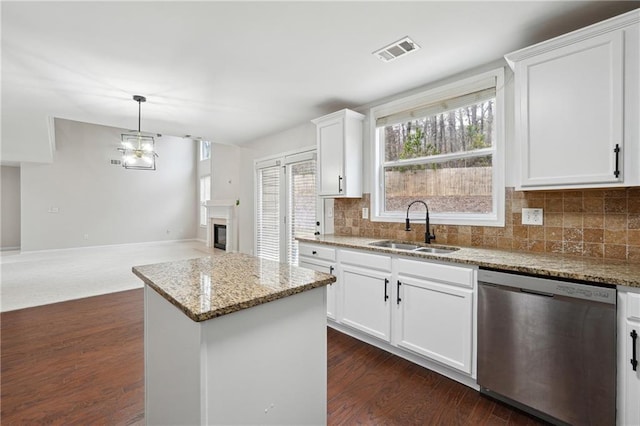 kitchen featuring sink, white cabinetry, a center island, light stone counters, and stainless steel dishwasher