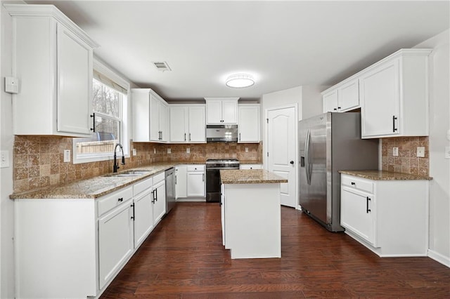 kitchen featuring appliances with stainless steel finishes, a center island, sink, and light stone counters