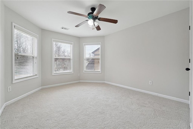 empty room with plenty of natural light, light colored carpet, and ceiling fan