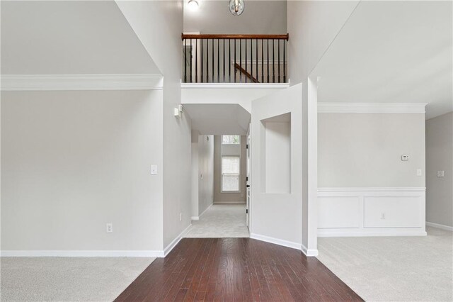 entrance foyer with ornamental molding, a chandelier, and dark colored carpet