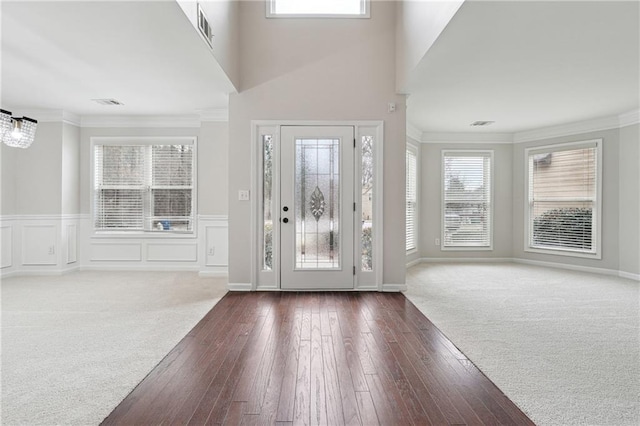 foyer entrance with ornamental molding and dark carpet