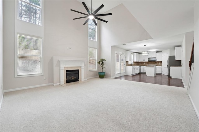 living room with a high ceiling, ceiling fan, carpet flooring, and a high end fireplace