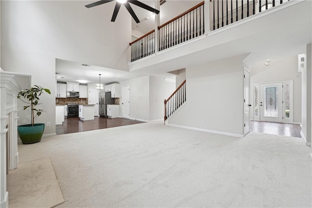 carpeted living room with ceiling fan and a high ceiling