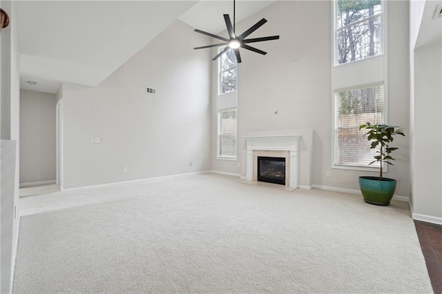 carpeted living room with ceiling fan, plenty of natural light, a fireplace, and high vaulted ceiling