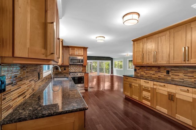 481 Patillo Rd, Stockbridge, GA 30281 - kitchen with appliances with stainless steel finishes, a sink, decorative backsplash, dark wood-style floors, and dark stone counters