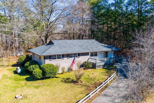 ranch-style home with a front lawn, roof with shingles, and a porch