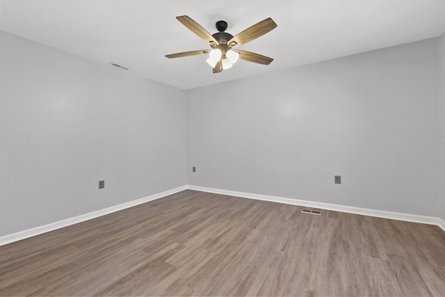 empty room featuring a ceiling fan, wood finished floors, visible vents, and baseboards