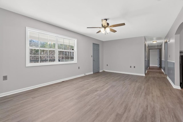 empty room with a ceiling fan, wood finished floors, attic access, and baseboards